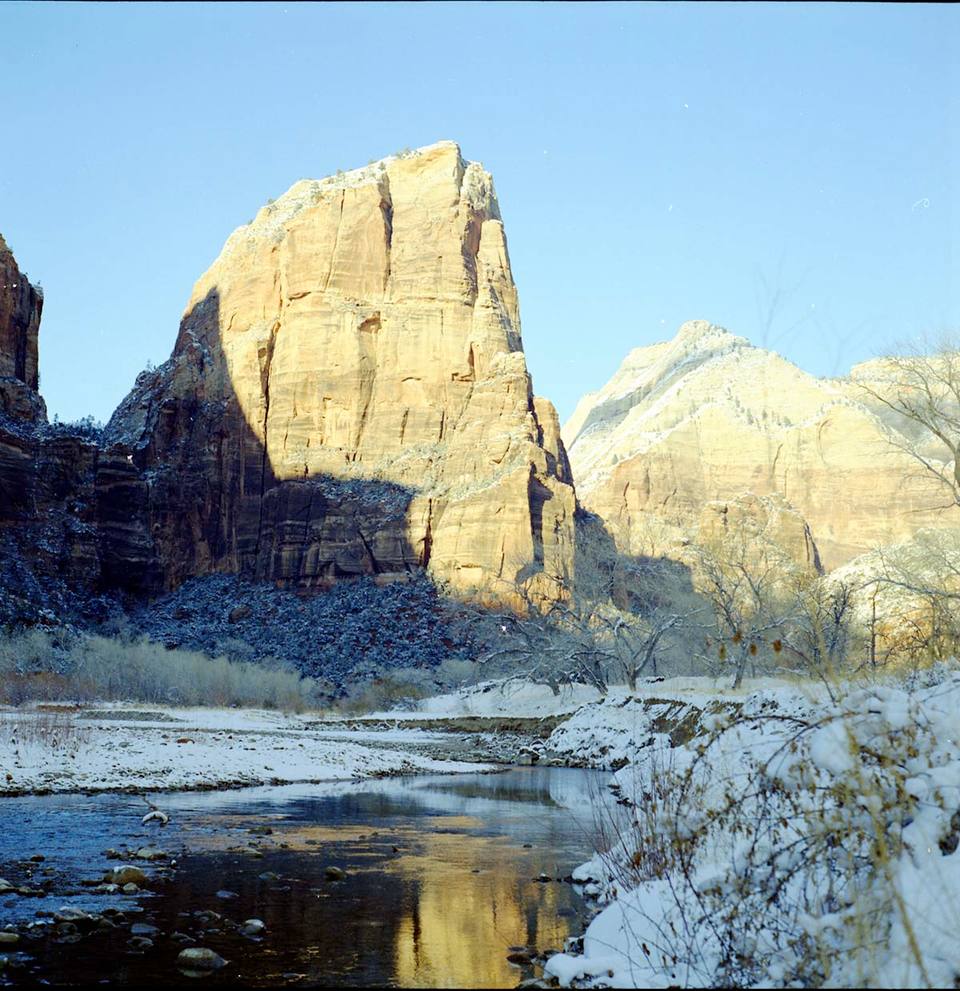 View of Angels Landing from canyon floor, snow along banks of the Virgin River., ZION Museum and Archives Image (7db67ae137a640edbfc7012872c7843a) — travel photo of Angels Landing, Zion & Springdale