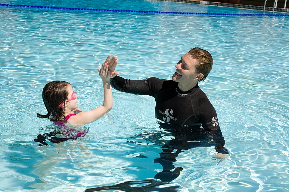US Navy -N-3271W- Chief Master-at-Arms Cris Miller swims with a young patron at Adventure Island waterpark — travel photo of Adventure Island, Tampa